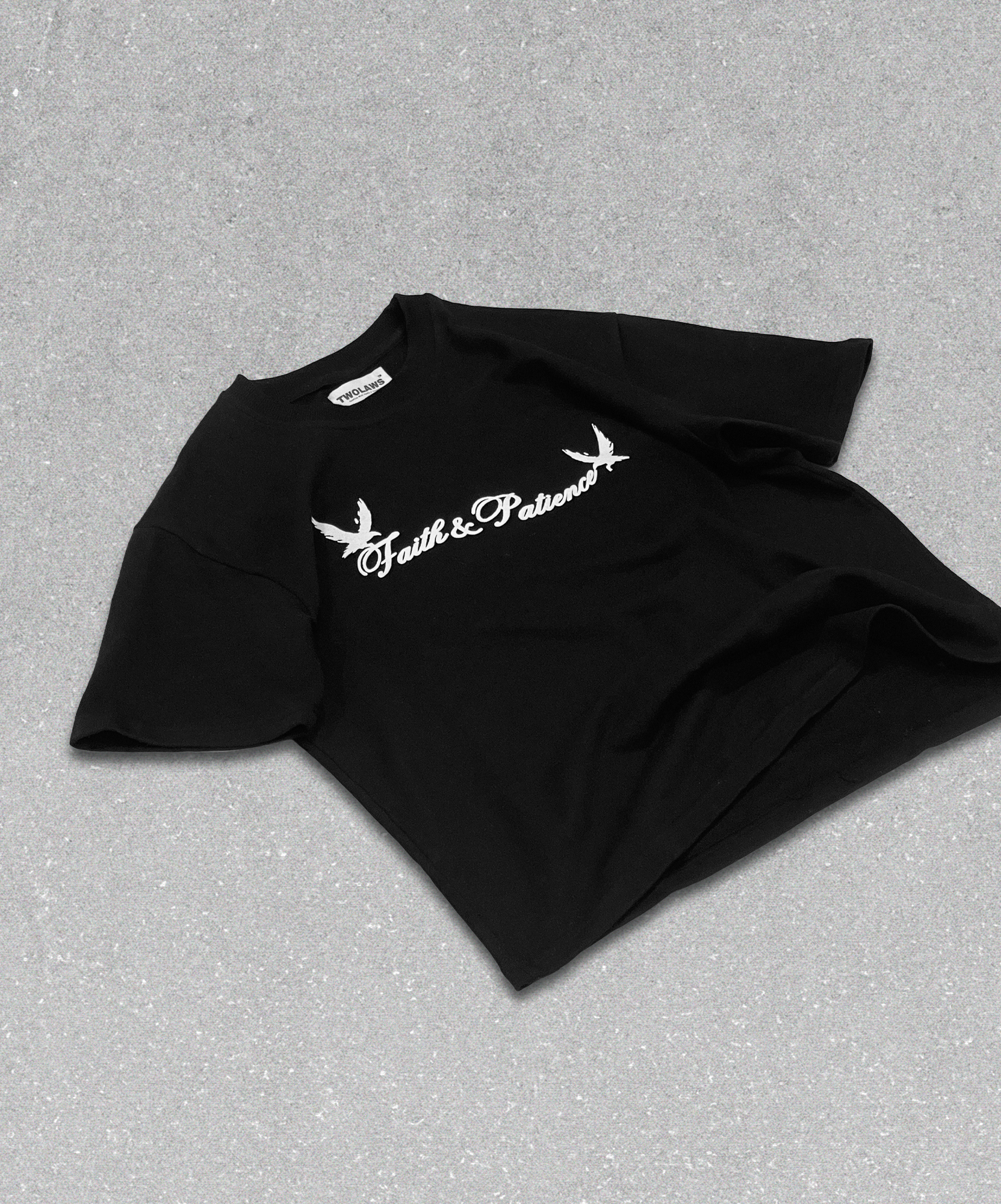 Front view of TWOLAWS Faith & Patience T-shirt Black with puff-printed text and twin bird design, laid flat on floor.