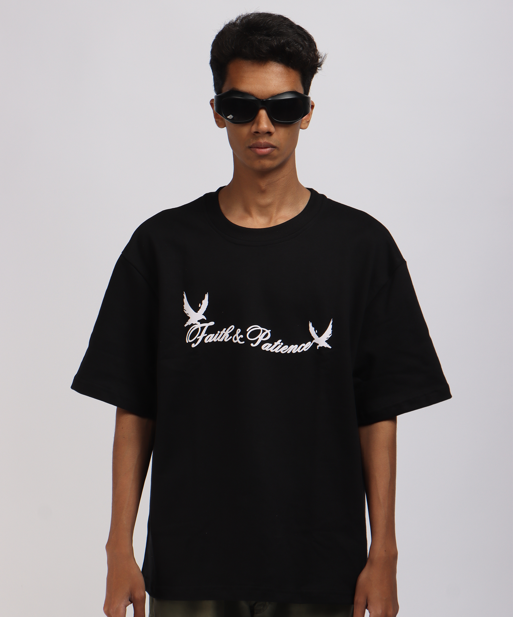 Model wearing Faith & Patience T-shirt Black, with puff print 'Faith & Patience' text with bird illustrations on the TWOLAWS oversized T-shirt.