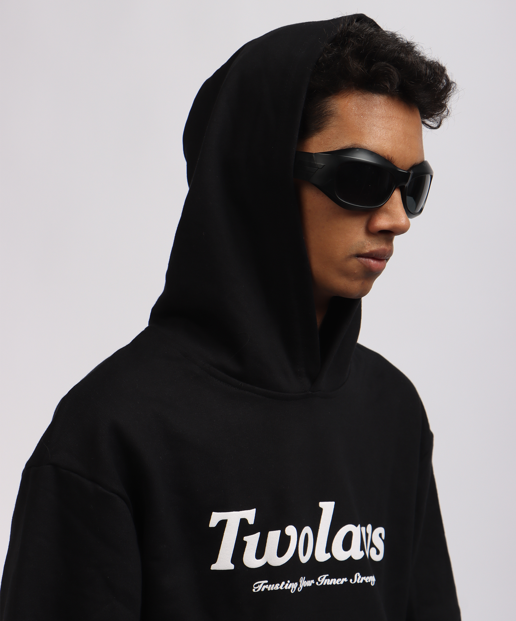 Close-up of model wearing TWOLAWS Black Hoodie featuring bold quote text across the chest and oversized fit.
